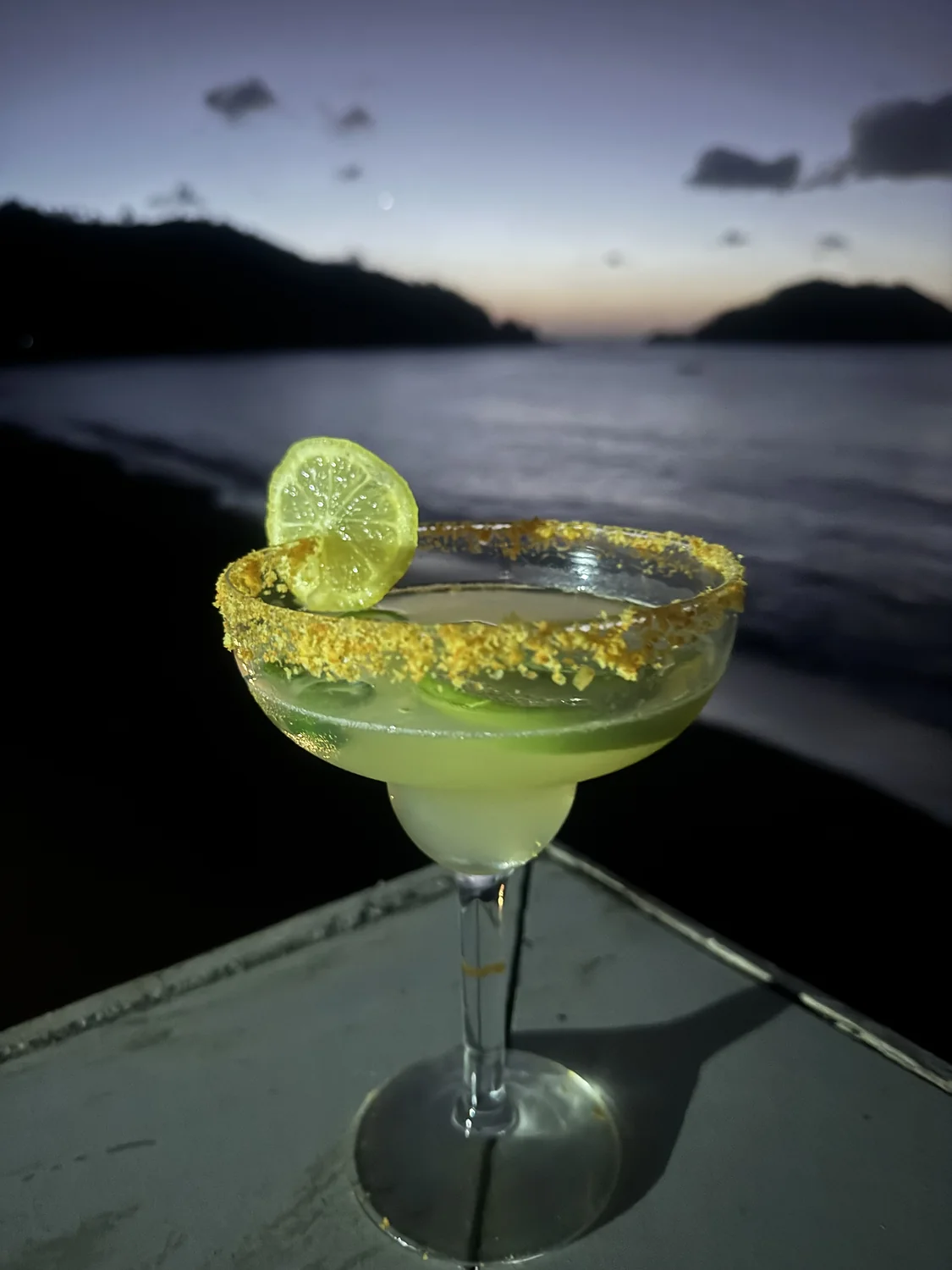 Craft cocktail on the Verandah rail as the sun sets over the water